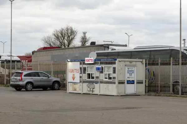 Bulgaria BGToll vignette and toll sales kiosk at border crossing with car queuing and signs in Bulgarian and English
